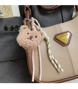 Vue détaillée d'un charm de sac ours en peluche kaki avec des cordes tressées bicolores