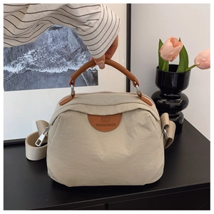Dettaglio della borsa a tracolla in nylon beige con logo in pelle marrone e zip argento
