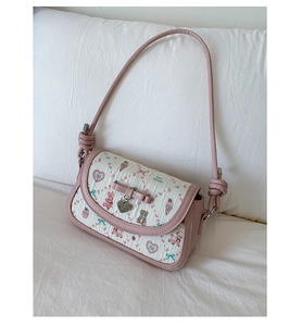 Detail showing pink ribbon bow and silver heart pendant on a floral cartoon bag