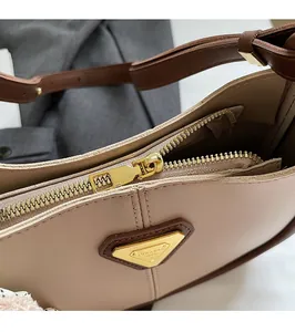 Gros plan sur la fermeture dorée et le logo métallique d'un sac cabas kaki chic