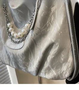Detail of silver crinkled tote bag featuring pearl and metal chain straps with leather tag