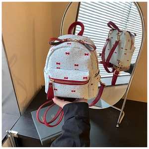Detail of light blue mini backpack with red bow prints and leather handle accents
