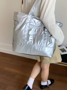 Grand sac cabas argenté métallisé avec broderie présenté dans un décor minimaliste