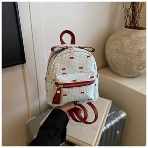 Detail of mini backpack featuring white bow print fabric and red leather straps