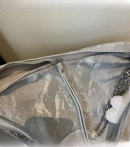 Close-up of silver textured bag with metal zipper and elegant pearl charm detail