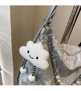 Detail of white plush cloud charm with striped legs on a silver textured bag with pearls