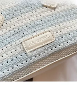 Macro shot of blue and white checkered woven tote bag with a leather logo patch