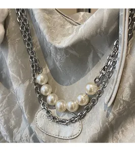 Detail of silver metallic textured bag with chunky chain strap and large white pearls