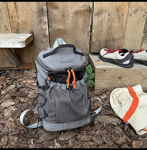 Detailed shot of grey outdoor backpack with orange zipper pulls and black mesh pocket