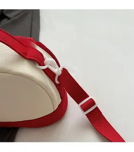 Detail of red adjustable fabric shoulder strap with durable white plastic hook