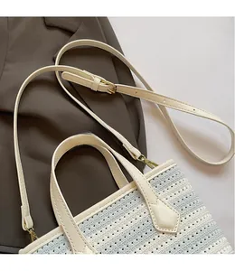 Detail of cream knit bucket bag showing crochet texture, leather handles, and gold strap hooks