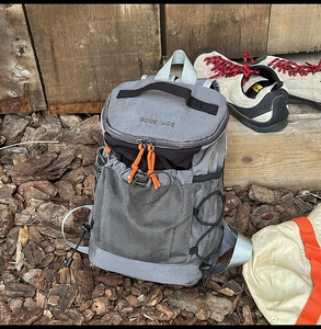 Detail of grey outdoor backpack with orange zipper pulls and adjustable side buckles