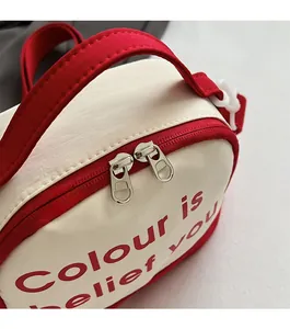 Detailed close-up of smooth double metal zippers on red and white canvas tote bag