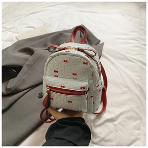 Close-up of mini backpack with red bow print and leather tassel detail on zippers