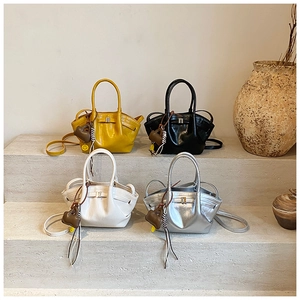 Detail view of four pleated tote bags in yellow, black, cream, and silver with charms