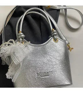 Détail du sac seau argenté plissé avec nœud en dentelle perlée et ferrures dorées
