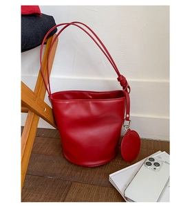 Detail der roten matten Leder-Beuteltasche mit rundem Münztäschchen auf Holzparkett