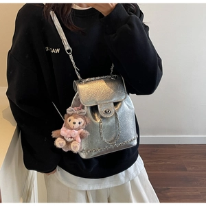 Detail eines silbernen Metallic-Rucksacks mit Wasserwellenstruktur und Kettenriemen