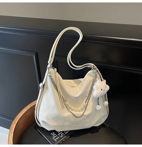Détail du sac hobo en cuir blanc avec chaîne argentée, perles et porte-clé nuage