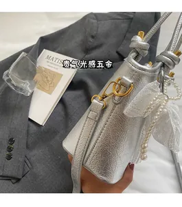 Vue détaillée du sac seau métallisé argenté avec perles et nœud décoratif en dentelle