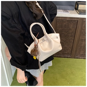 Detail of beige soft leather dumpling bag with elephant charm and smiling face tag