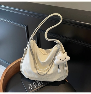 Détail du sac cabas blanc cassé avec chaîne argentée, perles et pendentif nuage en peluche