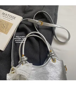 Détail du sac seau argenté métallisé orné d'un nœud en dentelle et perles dorées