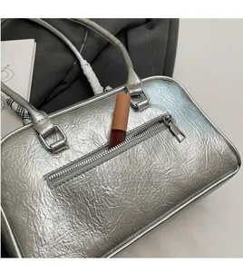 Macro shot of front zipper pocket on silver wrinkled leather Boston bag with lipstick