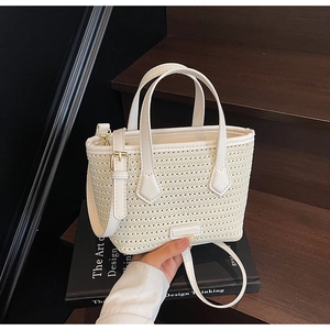 Detail view of white woven knit bucket bag with leather handles and metal hardware