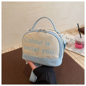 Detail of canvas mini bowling bag with contrasting leather trim and elegant top handle