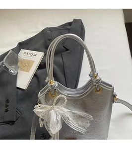 Détail du sac seau argenté métallisé avec texture craquelée et breloque noeud en perles