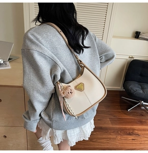Détail du sac fourre-tout blanc crème avec pendentif ours et logo doré triangulaire