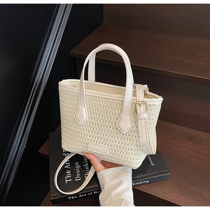 Close-up of cream woven bucket bag with leather handles and adjustable shoulder strap