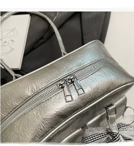 Close-up of silver wrinkled texture bag with smooth double zippers and bow detail
