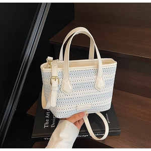 Detail of white knit bucket bag featuring metal logo and adjustable crossbody strap