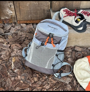 Detail of outdoor backpack featuring blue nylon fabric, white mesh pocket and orange zippers