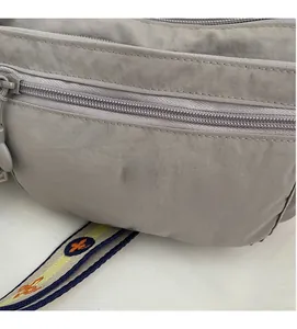 Close-up of dark grey oxford fabric bag featuring metal logo and smooth multi-layer zippers