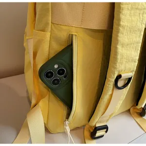 Detail of a yellow backpack featuring a hidden anti-theft zipper pocket on the back