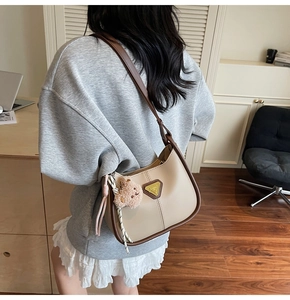 Détail du sac hobo beige et marron avec un adorable porte-clé en peluche d'ours