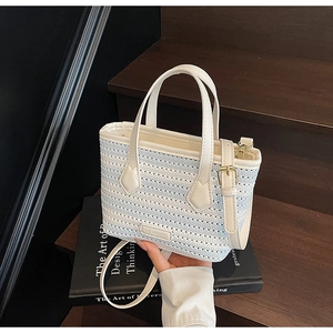 Detail of blue and white striped woven bucket bag with leather trim and gold hardware