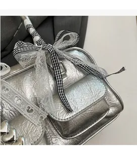 Detailed close-up of metallic silver pleated fabric with lace trim and bow on Boston bag