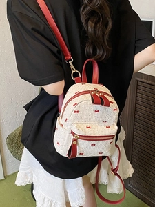 Mini cream woven backpack with red bow print and leather straps worn by a model