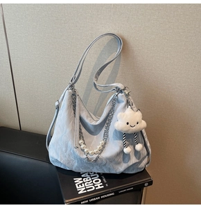Détail du sac plissé bleu clair avec chaîne en perles et accessoire de nuage blanc doux