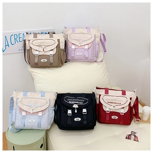 Detail showing five colors of contrast canvas messenger bags with flap buckle closures