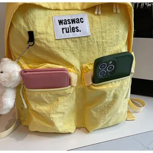 Detail showing two front pockets of a yellow nylon backpack storing a wallet and phone