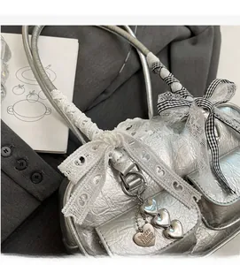 Detail of silver textured shoulder bag with lace bow accents and heart charms