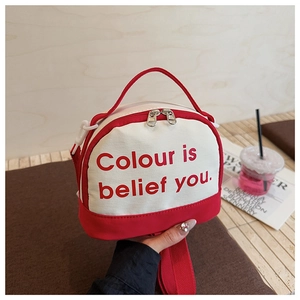 Close-up of a red and white mini crossbody bag with a slogan on a lifestyle background