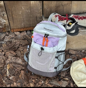 Detailed view of lightweight outdoor backpack with purple accents on a nature background