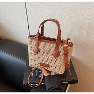 Close-up of beige woven bucket bag featuring brown leather trim and golden hardware