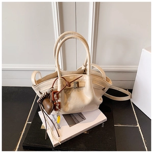 Detail of cream leather dumpling bag with heart pendant and adjustable shoulder strap